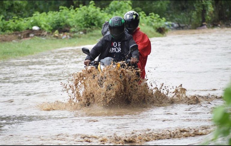 Dos hombres se transportan en motocicleta en una calle inundada por el desbordamiento del río Chamelecón, en la ciudad de San Pedro Sula, Honduras. EFE/J. Valle