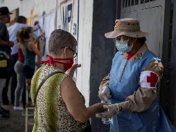 Una trabajadora da líquido desinfectante a una votante en una casilla hoy, en Caracas. EFE/ M. Gutiérrez