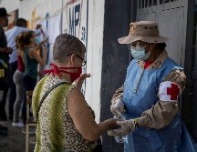 Una trabajadora da líquido desinfectante a una votante en una casilla hoy, en Caracas. EFE/ M. Gutiérrez