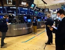 Corredores de bolsa protegidos con cubrebocas trabajan en Wall Street. AP/C. Ziemer