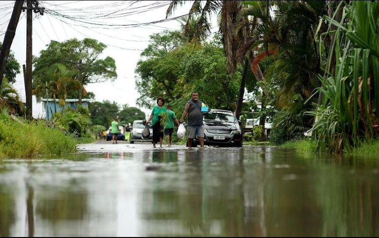 Varias personas caminan por calles inundadas tras el paso de 