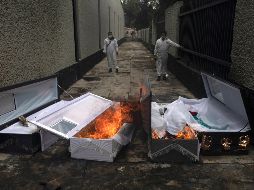 Empleados de una funeraria queman los ataúdes de personas fallecidas víctimas del COVID-19 luego de que sus cuerpos fueran incinerados en en el barrio Iztapalapa de la Ciudad de México. AP / M. UGARTE