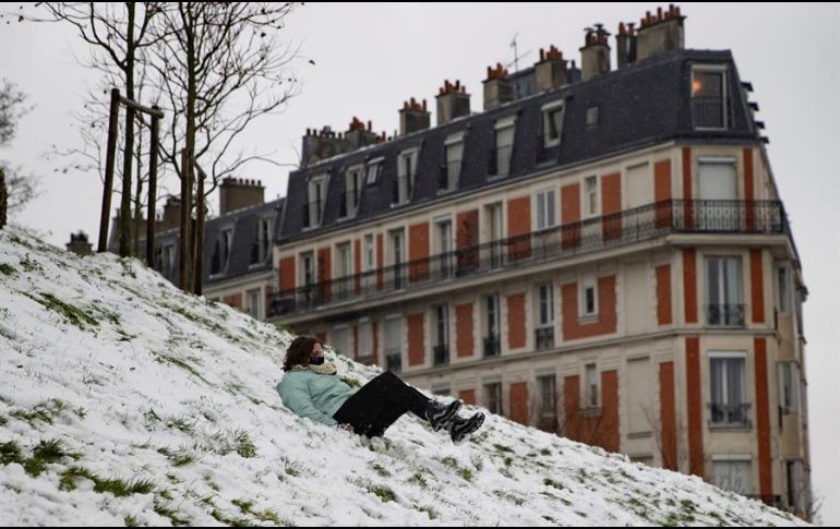 Una mujer protegida con cubrebocas se desliza por las laderas nevadas de Montmartre. EFE/I. Langsdon