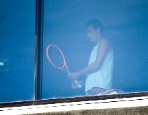 El tenista Bernard Tomic se ejercita hoy en un cuarto de hotel en Melbourne. Hay 72 tenistas en confinamiento estricto en sus habitaciones de hotel. AFP/W. West