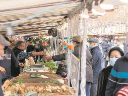 Botellas de gel y cubrebocas se observan entre los puestos de un tianguis parisino, pero no el control de la distancia. AFP