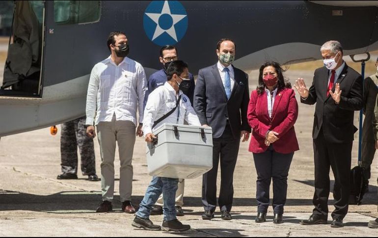 Un trabajador del Gobierno de Guatemala transporta vacunas (caja gris) donadas por Israel mientras ante la mirada del embajador de Israel en Guatemala (d), en el aeropuerto internacional La Aurora. EFE/E. Biba