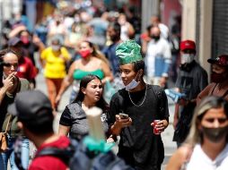 Dos jóvenes que no hacen uso correcto del tapabocas caminan en una concurrida calle comercial en Sao Paulo. EFE/S. Moreira
