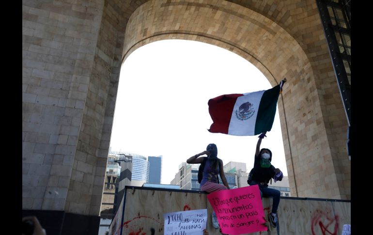 Mujeres ondean una bandera mexicana desde arriba de una de las protecciones. AP/R. Blackwell