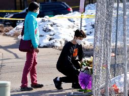 Un joven deja flores junto a una reja colocada alrededor del estacionamiento del supermercado donde ayer se registró el tiroteo en Boulder, Colorado. AP/D. Zalubowski