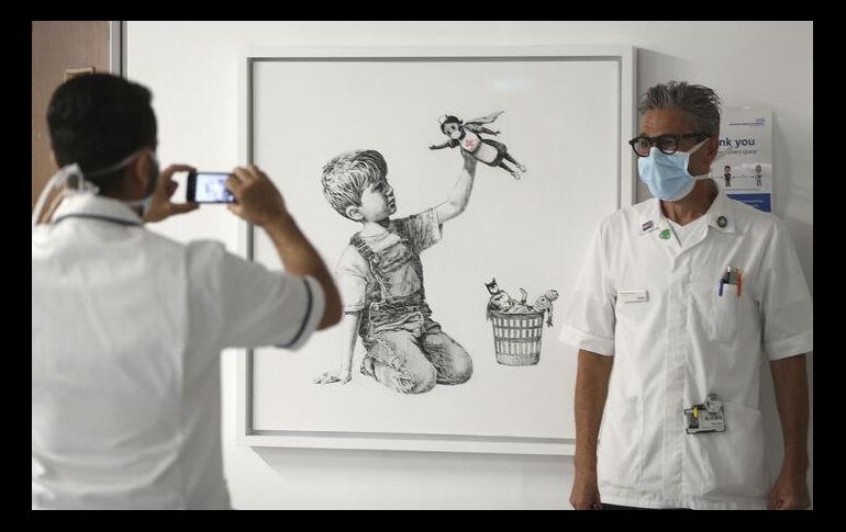 La pintura en blanco y negro muestra a un niño sentado en el piso jugando con una muñeca de enfermera superheroína. AP / ARCHIVO