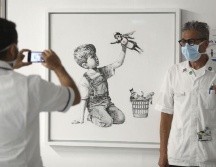La pintura en blanco y negro muestra a un niño sentado en el piso jugando con una muñeca de enfermera superheroína. AP / ARCHIVO