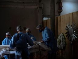 Enfermeros acomodan el cuerpo de un fallecido en una morgue improvisada en la iglesia del hospital Centenario, en São Leopoldo, Rio Grande do Sul. EFE/D. Marenco