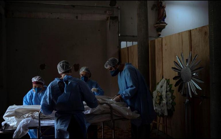 Enfermeros acomodan el cuerpo de un fallecido en una morgue improvisada en la iglesia del hospital Centenario, en São Leopoldo, Rio Grande do Sul. EFE/D. Marenco
