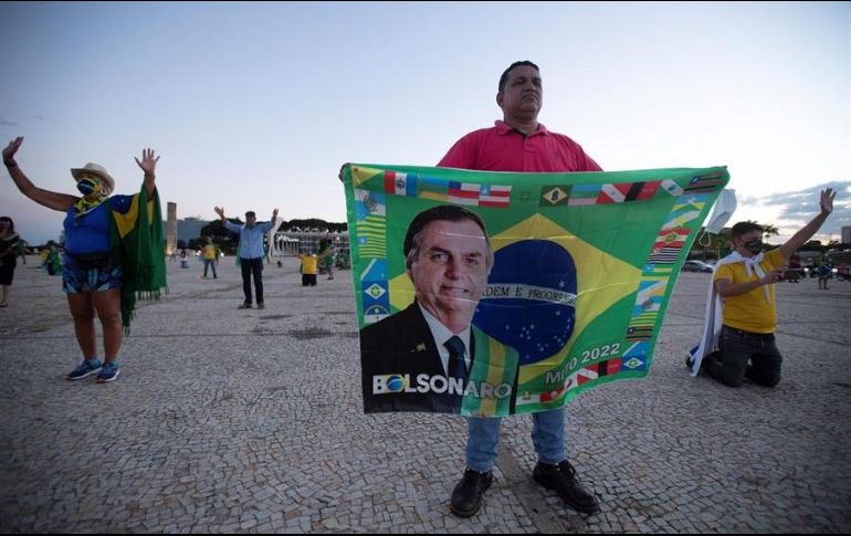 Seguidores del presidente de Brasil, Jair Bolsonaro, rezan durante una protesta contra el cierre comercial debido a la pandemia de coronavirus, en Brasilia. EFE/J. Alves