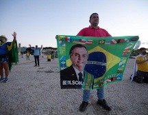 Seguidores del presidente de Brasil, Jair Bolsonaro, rezan durante una protesta contra el cierre comercial debido a la pandemia de coronavirus, en Brasilia. EFE/J. Alves