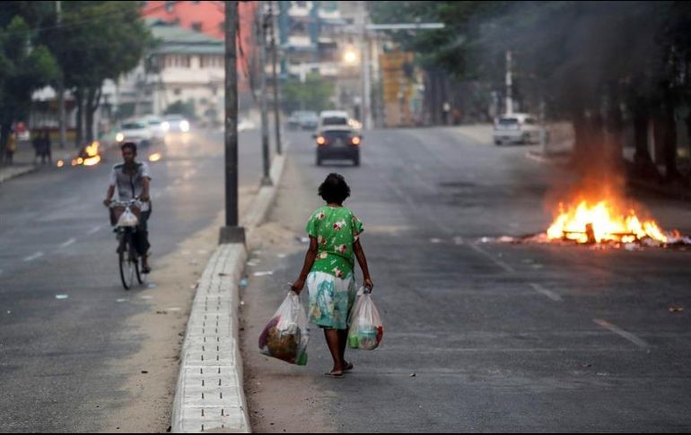 Personas se desplazan por una calle junto a hogueras que simbolizan la resistencia contra el golpe de Estado este miércoles en Rangún, Birmania. EFE