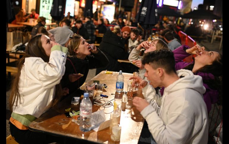 Jóvenes toman tequila en la parte exterior de un bar en la ciudad de Manchester. AFP/O. Scarff