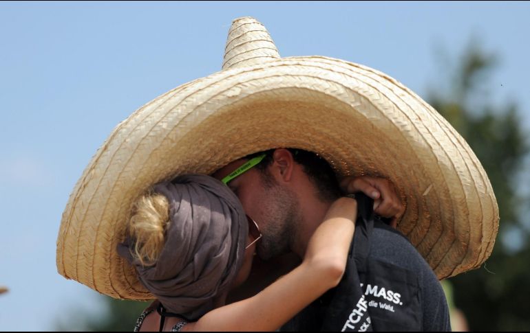 Una pareja se besa bajo un enorme sombrero en el Festival de Greenville en Paaren im Glien, en el norte de Alemania, el 28 de julio de 2013. AFP / ARCHIVO