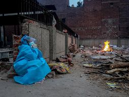 Una persona con traje de protección observa la cremación de un familiar, muerto por COVID-19. EFE/R. Gupta
