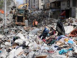 Una máquina excavadora retira hoy escombros de un edificio destruido en la Ciudad de Gaza, luego de un bombardeo de Israel. AFP/M. Hams