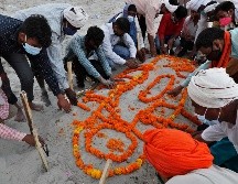 Personas entierran hoy el cuerpo de un familiar que no murió por COVID-19, en una tumba en la arena junto a la orilla del río Ganges, en Prayagraj. La policía dijo que ya no permitirá entierros en la ribera. AP/R. Kumar Singh