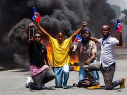 Manifestantes protestan en medio de la celebración del Día de la Bandera, en Puerto Príncipe, la capital de Haití. EFE/J. Herve