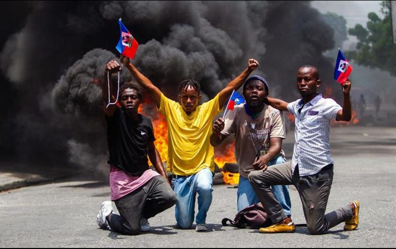 Manifestantes protestan en medio de la celebración del Día de la Bandera, en Puerto Príncipe, la capital de Haití. EFE/J. Herve