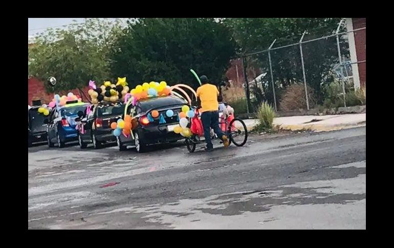 En la publicación se puede ver a un hombre formado en la fila de coches con su triciclo adornados de globos de colores. Facebook / T. Coronel