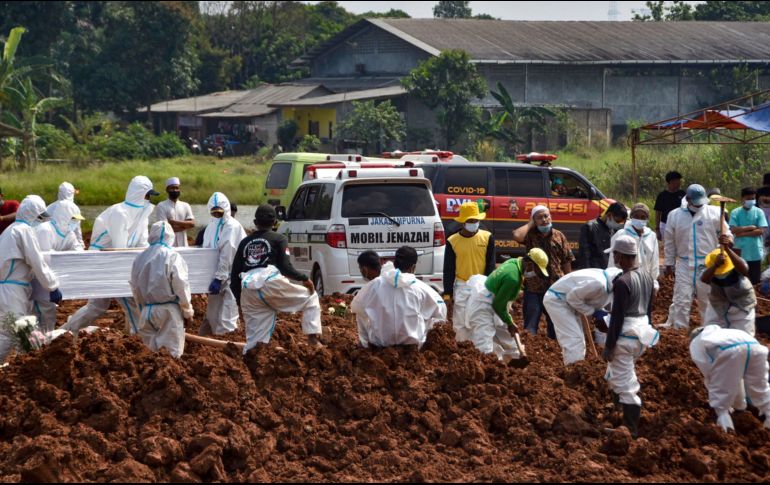Trabajadores entirran hoy cuerpos de víctimas de COVID-19 en un cementerio público en Bekasi, Indonesia. AFP/Rezas