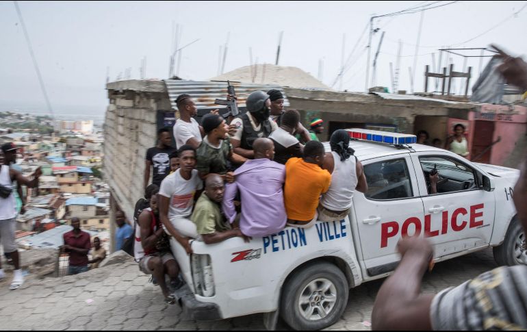 Un carro de la Policía traslada a dos sospechosos de participar en el asesinato de Moise a la estación Petionville en Puerto Príncipe, Haití. AFP/V.  Baeriswyl