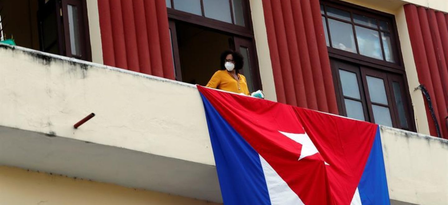 Una mujer sale al balcón donde se expone una bandera cubana, este martes en La Habana. EFE/E. Mastrascusa