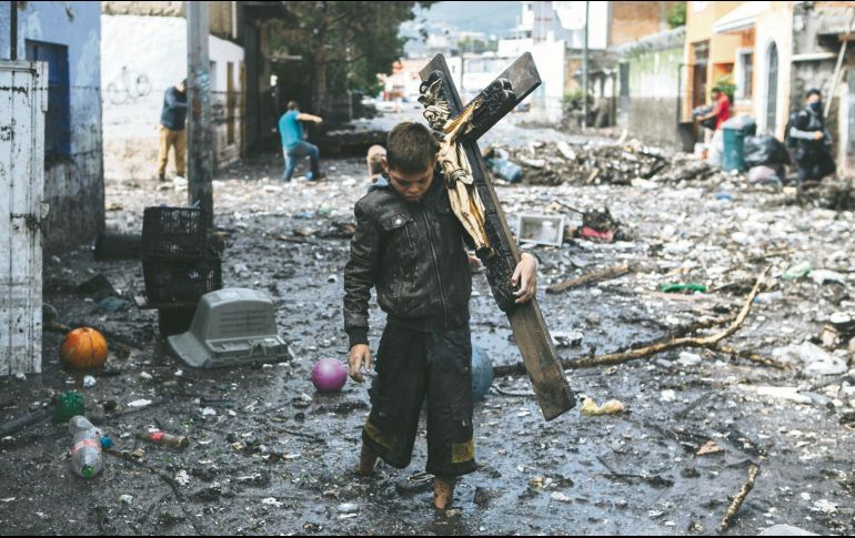 TRAGEDIA. Con una cruz a cuestas un vecino de Paulina ayuda a buscar pertenencias que ve flotando entre los escombros en la Calles Costa Chica. G.GALLO