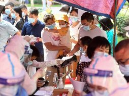 Habitantes hacen fila hoy para que les tomen tests de COVID-19 en Wuhan, China, pues la ciudad hace pruebas a toda su población. AFP