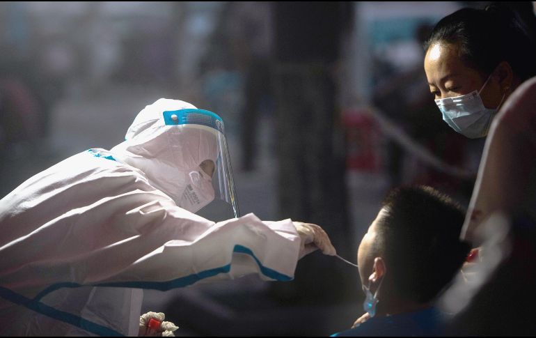 PRUEBAS. Un trabajador médico toma una muestra de hisopado de un residente para una prueba de ácido nucleico de COVID-19, en Wuhan, en China. La ciudad lanzó el martes una nueva ronda de pruebas para detectar contagios entre su población. XINHUA