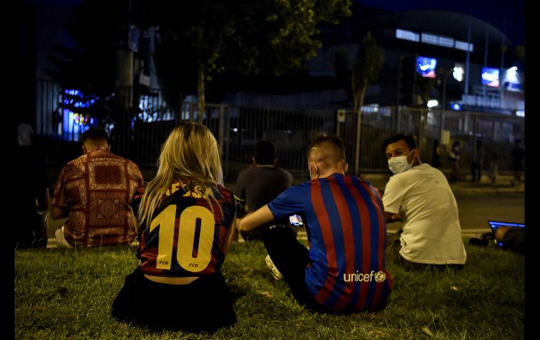 Con camisetas blaugranas, los aficionados se sentaron incrédulos afuera de las instalaciones del club. AFP/P. BARRENA