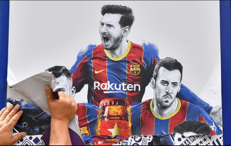 Un trabajador quita un cartel de Liones Messi en el Nou Camp, en Barcelona. AFP/P. Barrena