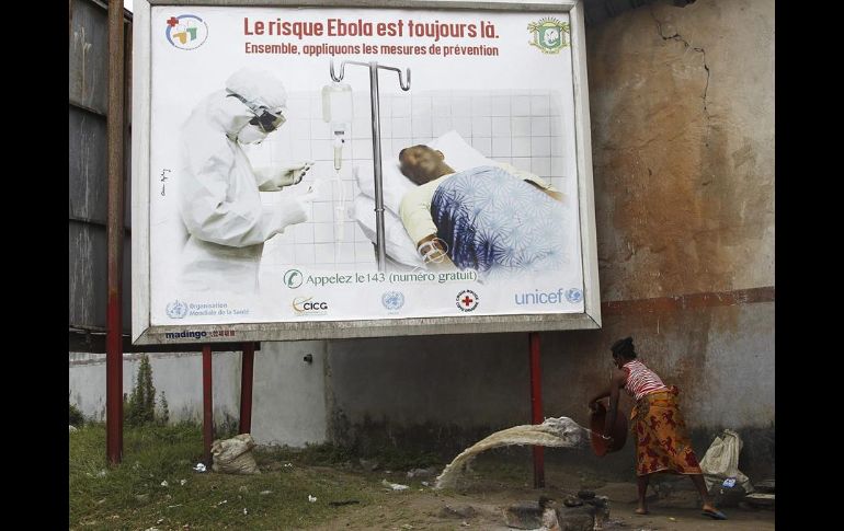 Una mujer desocupa un balde con agua debajo de una valla de advertencia sobre la presencia del virus del ébola, el 25 de agosto de 2014. EFE/ARCHIVO