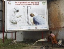 Una mujer desocupa un balde con agua debajo de una valla de advertencia sobre la presencia del virus del ébola, el 25 de agosto de 2014. EFE/ARCHIVO