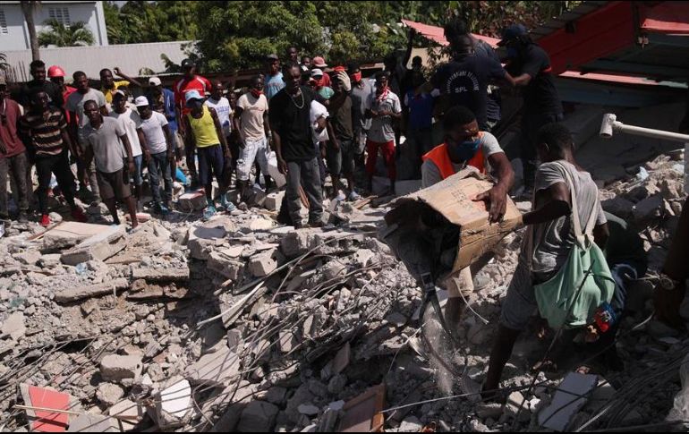 Un grupo de personas remueve escombros en una calle de Los Cayos. EFE/O. Barría