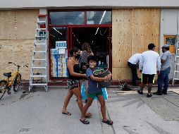 Trabajadores colocan protecciones en un negocio esta tarde en Tulúm, Quintana Roo, previo a la llegada del huracán 