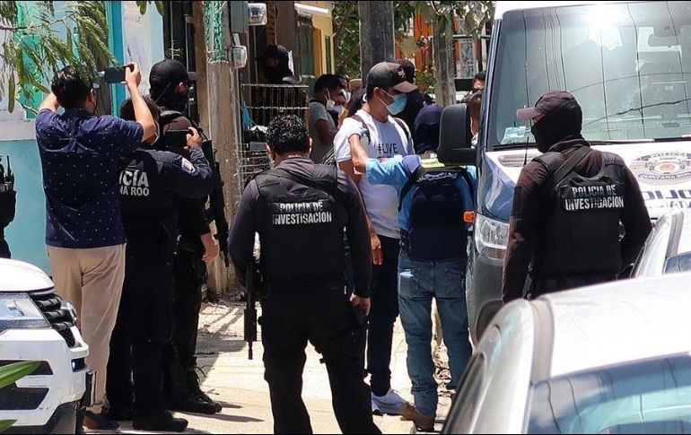 Agentes de la Policía Ministerial de la Fiscalía General Estatal escoltan a un grupo de migrantes asegurados en una casa de la ciudad de Cancún. EFE/A. Cupul
