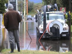 Una persona observa un camión drenar la presión del agua debido a las lluvias tras el paso del huracán 