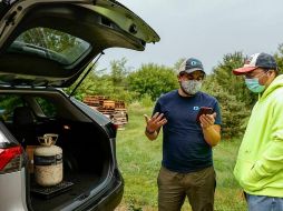 Chad Dorger (izq), del Programa Ambiental en Tradewater, recoge los tanques de refrigerante vacíos de Rick Karas. AFP