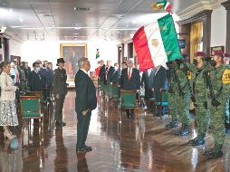 A LA MITAD DEL CAMINO. López Obrador sostiene una bandera nacional antes de rendir su Tercer Informe anual del gobierno en Palacio Nacional. AFP