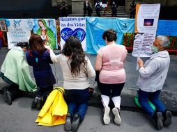 Un grupo de mujeres en contra del aborto rezan frente a carteles de protesta 