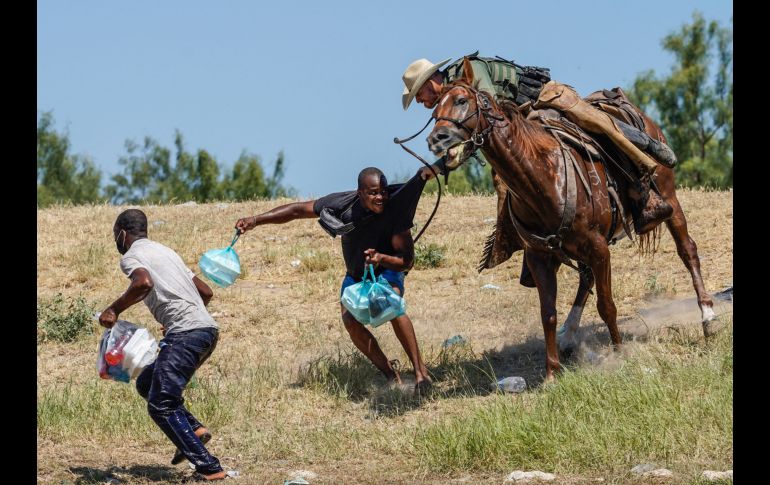 Un agente de la Patrulla Fronteriza de EU intenta impedir que un haitiano ingrese al campamento cerca del puente internacional de Del Río, Texas. AFP/P. Ratje