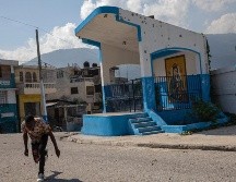 Un hombre corre para protegerse al cruzar una calle barridaca en el barrio Bel Air, controlado por una pandilla, en Puerto Príncipe. AP/R. Abd