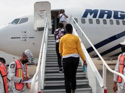 Elementos de la Guardia Nacional se ven en el aeropuerto de Villahermosa, mientras haitianos se suben a un avión que los llevará a Puerto Príncipe. AFP/INM