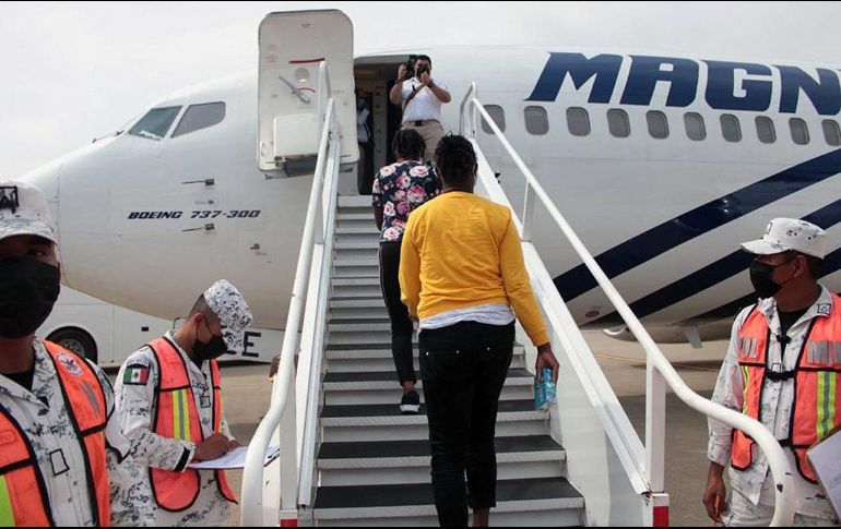 Elementos de la Guardia Nacional se ven en el aeropuerto de Villahermosa, mientras haitianos se suben a un avión que los llevará a Puerto Príncipe. AFP/INM