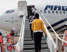Elementos de la Guardia Nacional se ven en el aeropuerto de Villahermosa, mientras haitianos se suben a un avión que los llevará a Puerto Príncipe. AFP/INM